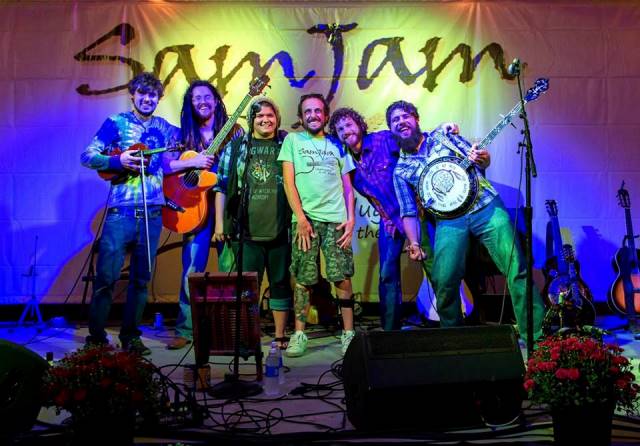 Sam Oswald poses on stage with ClusterPluck, one of the bands that performed at SamJam, Unplugged on the Prairie, September 27